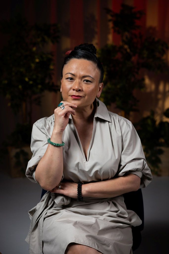 An image of Pauline Nguyen with one arm across her body, and the other to her chin.